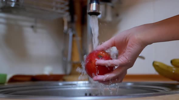 Female Washes Ripe Red Apple with Stream Running Water From a Tap in Kitchen