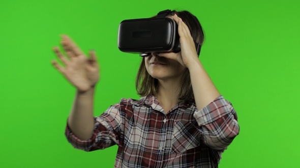 Girl Using VR App Helmet To Play Simulation Game. Slide Gestures. Watching Virtual Reality 3d Video