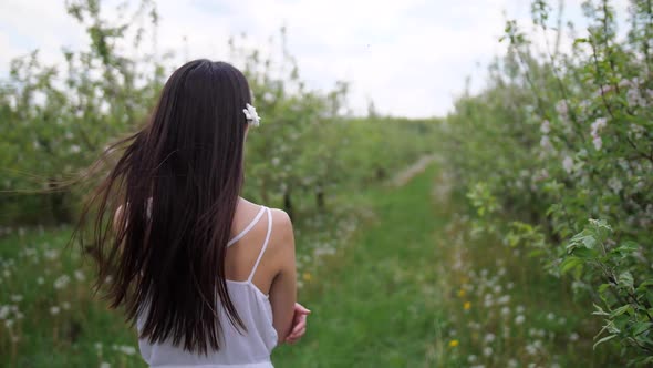 Brunette Female Walking Among Flowering Trees