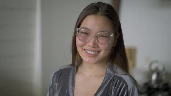 Cheerful Young Beautiful Asian Woman in Eyeglasses Looking at Camera Smiling Indoors