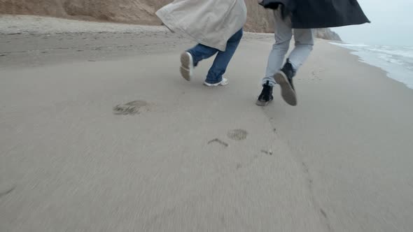 Happy Couple Run on the Wild Beach on Cloudy Sunrise