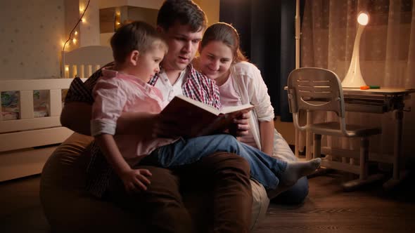 Happy Family with Little Boy Reading Book at Night Before Going To Sleep