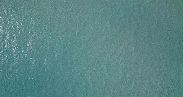 Wide angle birds eye abstract shot of a white sand paradise beach and blue water background 