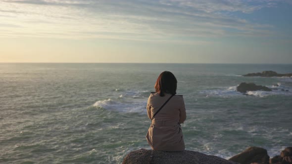 A Girl in a Cloak Looks at the Sea at Sunset