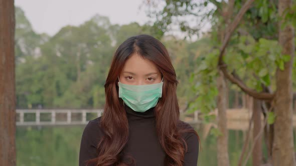 Thai Young Woman Slowly Looks Up Into the Camera in the Park at Sunset