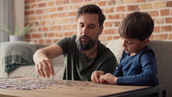 Handheld video of boy solving jigsaw puzzle with father. Shot with RED helium camera in 8K.