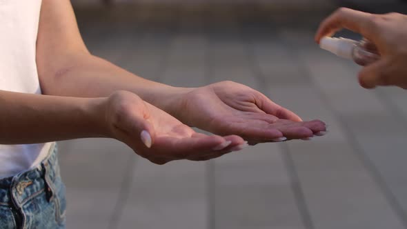 Side View of the Girl's Hands Sprinkled with Alcohol Antiseptic for Disinfection and Protect From