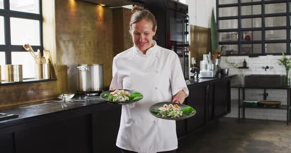 Caucasian female chef preparing a dish and smiling in a kitchen