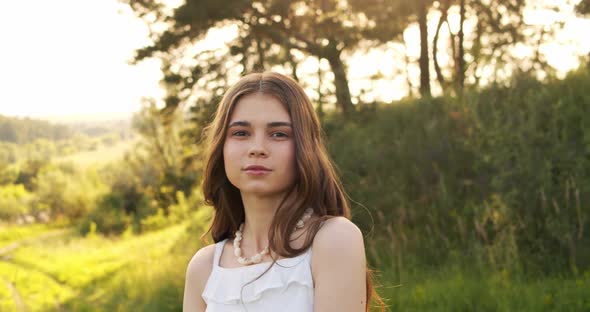 Attractive European Chestnut Teen Girl with Natural Makeup Looks Into the Camera in Nature on a