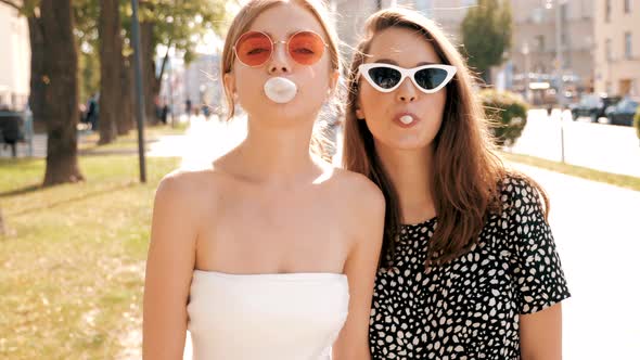 Portrait of two young beautiful smiling hipster girls in trendy summer clothes
