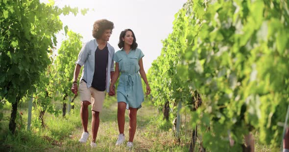 Romantic Love Couple, Man and Woman Smiling and Walking Near Vineyard at Sunset or sunrise.Warm Sun