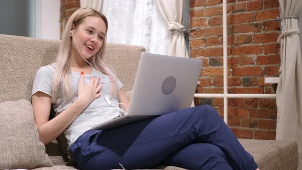 Woman Doing Video Chat on Laptop, Sitting on Sofa at Home