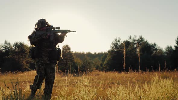 Silhouette of Armed Men, Taking Aim Through the Weapon Goes Ahead