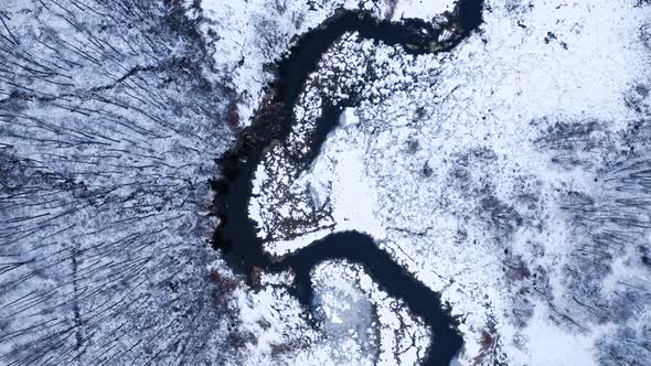 Cold river and snowy forest. Aerial view of winter nature