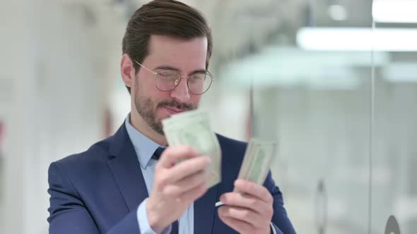 Successful Young Businessman Counting Dollars