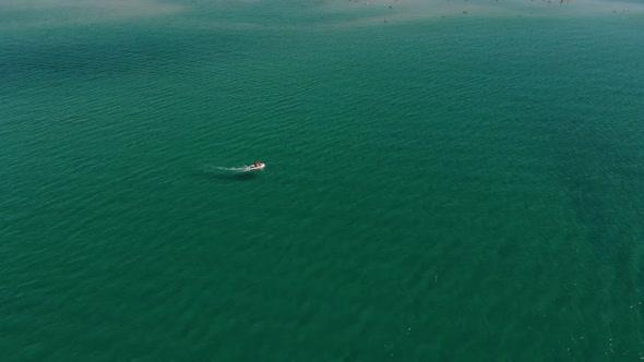 Aerial View of a Motor Boat Cruising Across the Clear Turquoise Sea on a Sunny Day