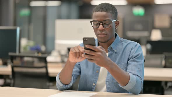 Attractive Young African American Man Using Smartphone in Office