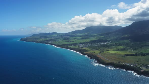 Bird's eye view of blue sea, black coast, green fields and wooded mountains in Saint Kitts and Nevis