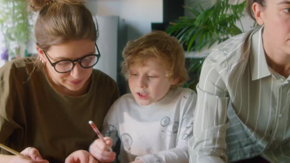 Kid Doing Homework with Assistance of Lesbian Mothers