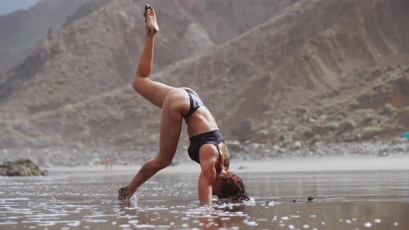 Girl Doing Yoga on the Shore of the Ocean on the Beach