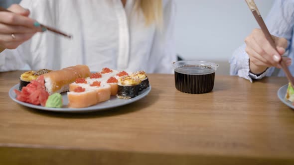 Close-up Shot of a Two Plates of Different Sushi Rolls, Girl Eating Sushi with Chopsticks