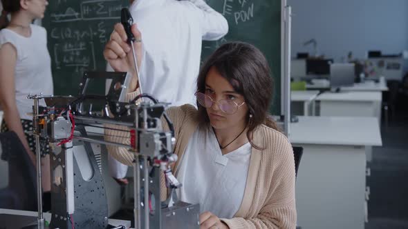 Girl Do the Work with the 3D Printer Teacher Next to the Blackboard