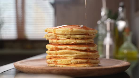 Pouring Maple Syrup Over Stack of Pancakes