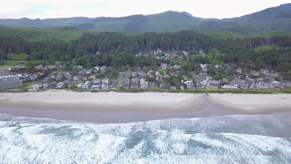 Aerial flying over Pacific Ocean revealing the town of Cannon Beach Oregon