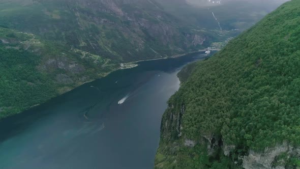 Aerial Slomo shot of Geiranger Fjord, Norway, with aing Boat and Local Town in the background