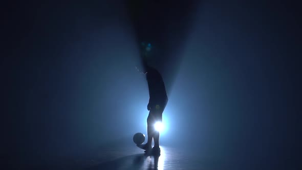 Football Freestyle. Silhouette of Freestyler at Studio Against Blue Spotlight, Slow Motion