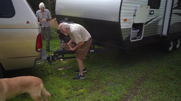 Woman tries to remove tire locking chock on travel trailer RV.