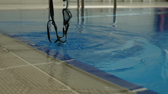 Woman Swimmer Rinses Out Her Swimming Goggles In a Pool