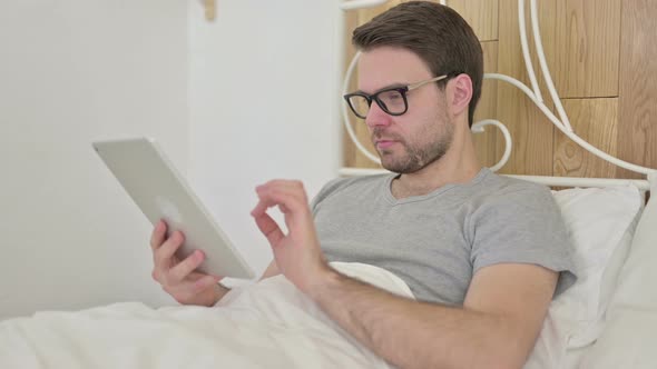 Beard Young Man Celebrating Success on Tablet in Bed