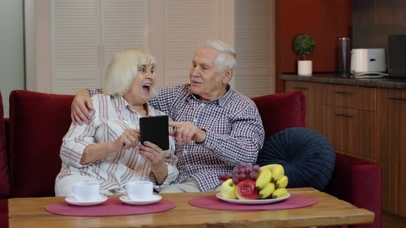 Senior Grandparents Couple Talking and Using Digital Tablet Computer at Home. Coronavirus Lockdown