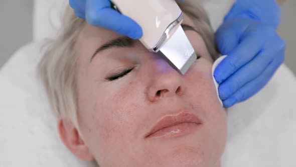 Ultrasonic peeling of the facial skin. Top view of a woman's face, close-up. Slow motion.