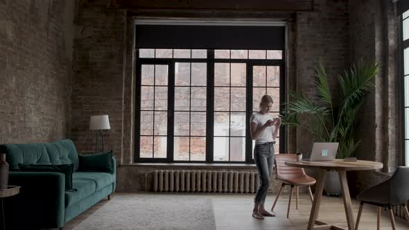 Woman in the white t-shirt holding a smartphone in hands and typing on its screen while chatting