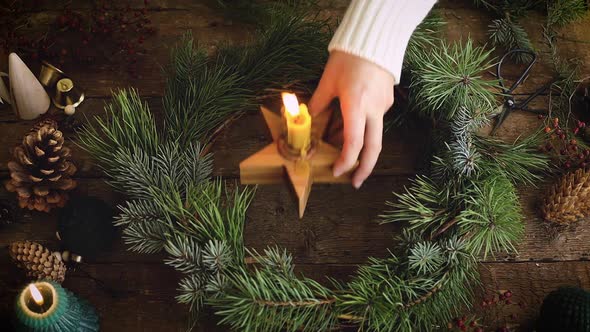 Burning candle in christmas wreath on rustic table, top vie