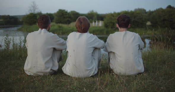 Young Guys are Sitting on the Bank of the River