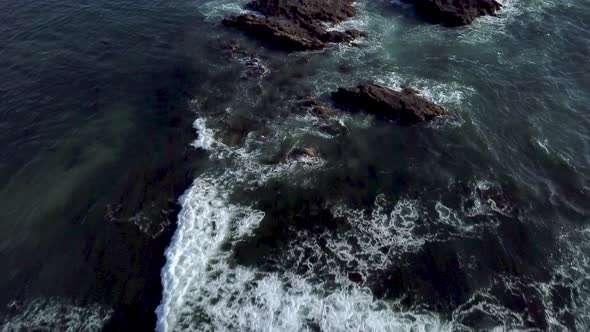 Dramatic aerial view of isolated Southern California coastal rock formations with waves splashing