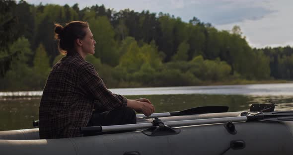 Young Beautiful Girl Sits in an Inflatable Boat on the Lake