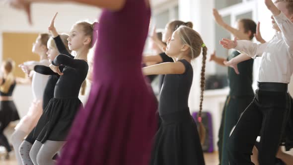 Group of Elegant Caucasian Children Rehearsing Waltz in Fourth Position in Dancing School