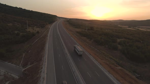 Truck Driving On The Asphalt Road In Rural Landscape At Sunset