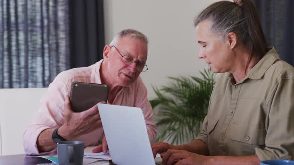 Caucasian senior couple using laptop and digital tablet at home