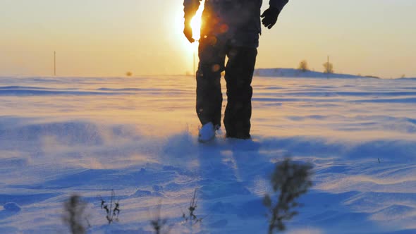 Silhouette of Man with a Backpack Walking in a Winter Landscape at Sunset