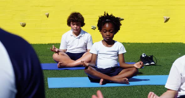 Yoga instructor instructing children in performing yoga