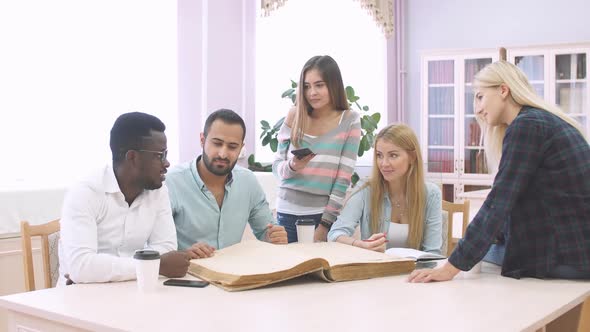 Girl with Glasses Reads Big Book with Blank Cover in Library