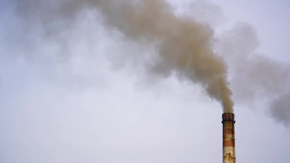 Pollution by industrial production. Fuming pipe power plant against the cloudy sky