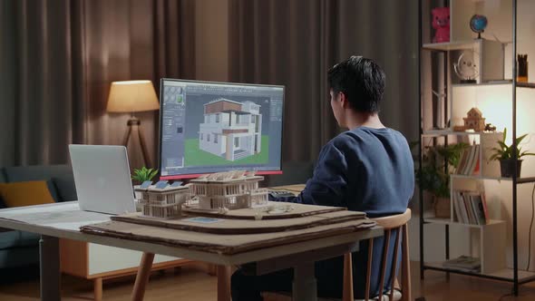 Asian Male Engineer Rotate And Zoom In 3D House While Working On A Desktop At Home