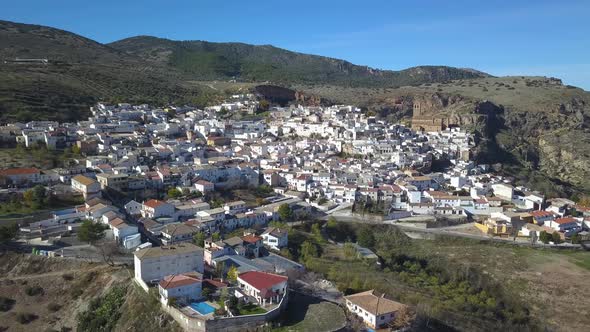 Aerial view of a traditional spanish white village in the mountains with a big chuch.