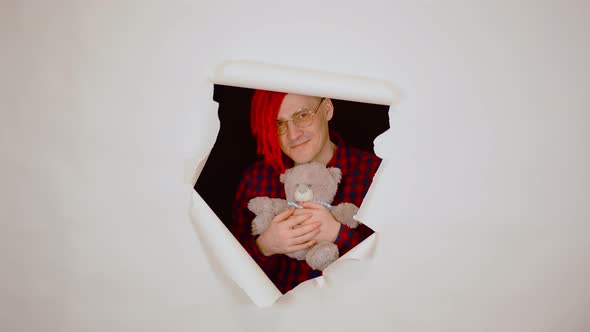 Young Man with Teddy Bear Looking Out of Hole of White Background